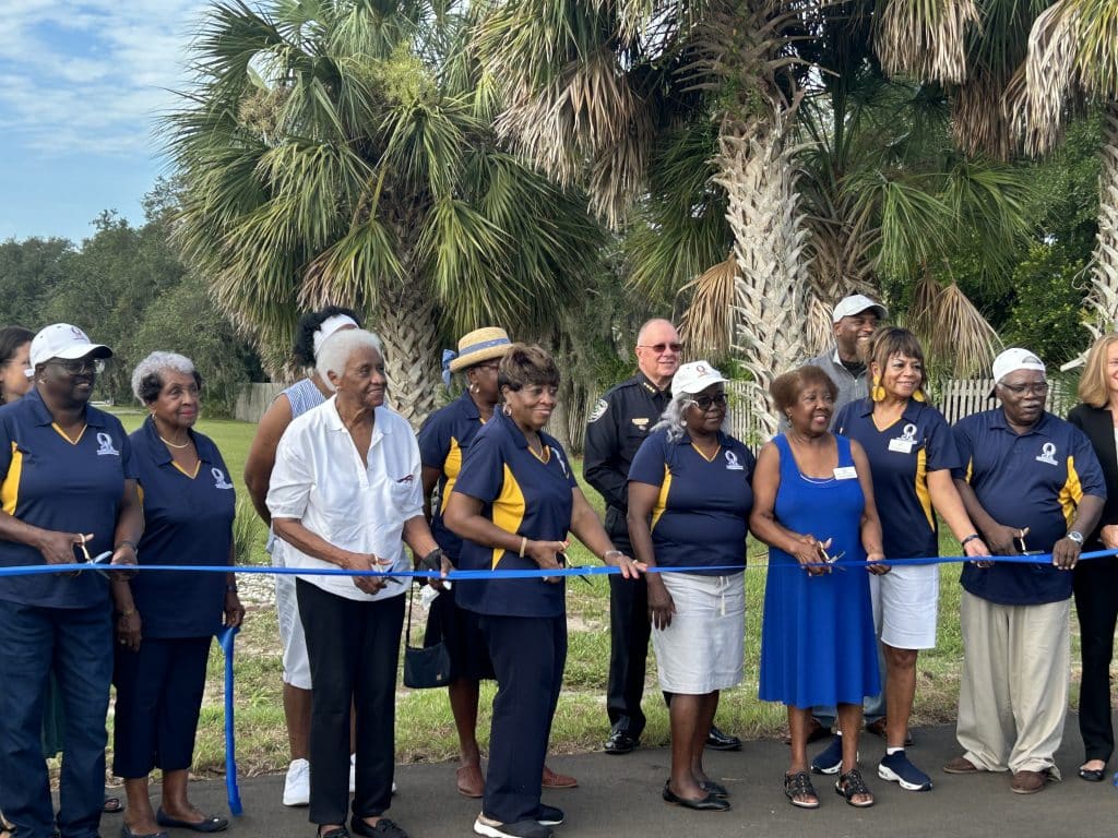 a group of people cut the blue ribbon honoring the new road