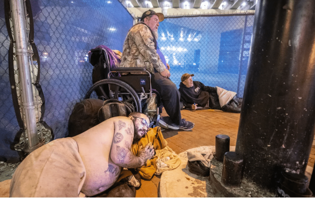 Ricky Guerrero, front, Jeff Castner, middle, and Mark Jarrett, back, prepare to sleep in their nightly spot on the streets of downtown Orlando on Friday, Dec. 13, 2024.