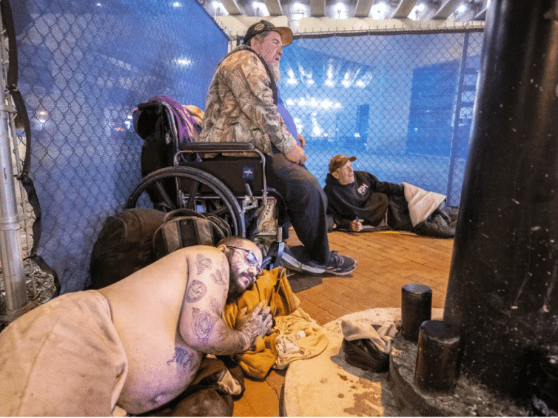 Ricky Guerrero, front, Jeff Castner, middle, and Mark Jarrett, back, prepare to sleep in their nightly spot on the streets of downtown Orlando on Friday, Dec. 13, 2024.