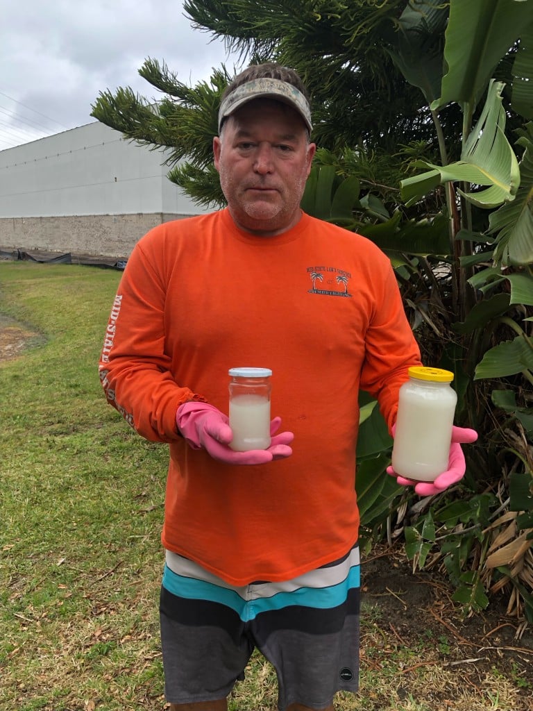 David Lockwood holding samples he took of the white liquid that was discharging from the pipe into the pond